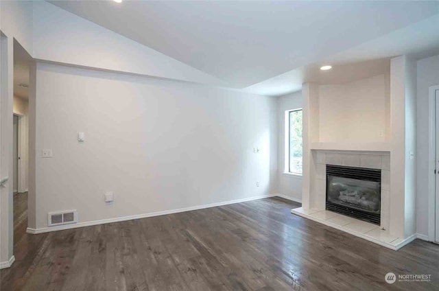 unfurnished living room featuring vaulted ceiling, a fireplace, and hardwood / wood-style floors