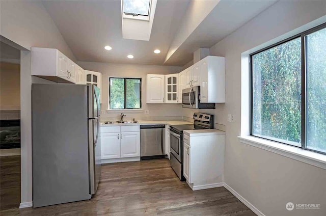 kitchen with white cabinetry, stainless steel appliances, vaulted ceiling with skylight, and a wealth of natural light