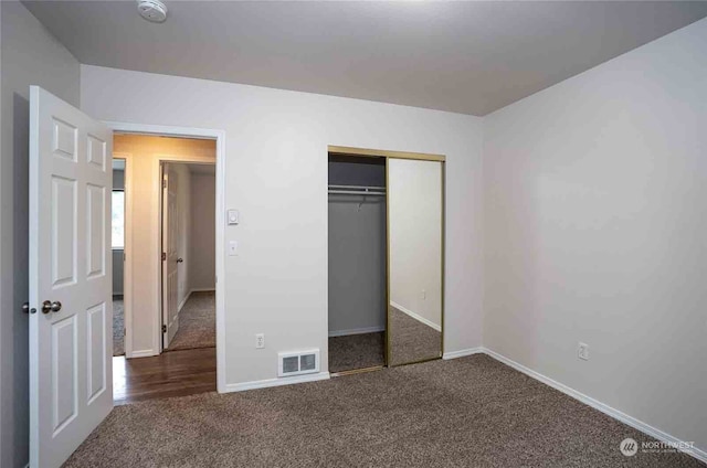 unfurnished bedroom with a closet and dark colored carpet