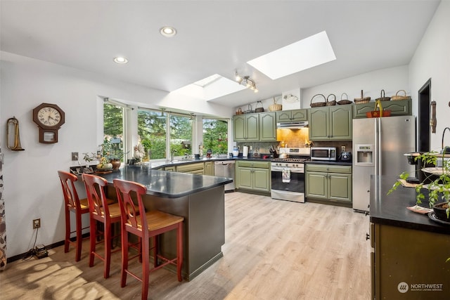 54611 278th Ave E, Ashford, WA 98304 - kitchen with a peninsula, vaulted ceiling with skylight, under cabinet range hood, appliances with stainless steel finishes, and green cabinetry