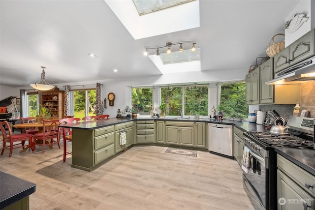 kitchen with a skylight, kitchen peninsula, green cabinetry, light hardwood / wood-style flooring, and stainless steel appliances