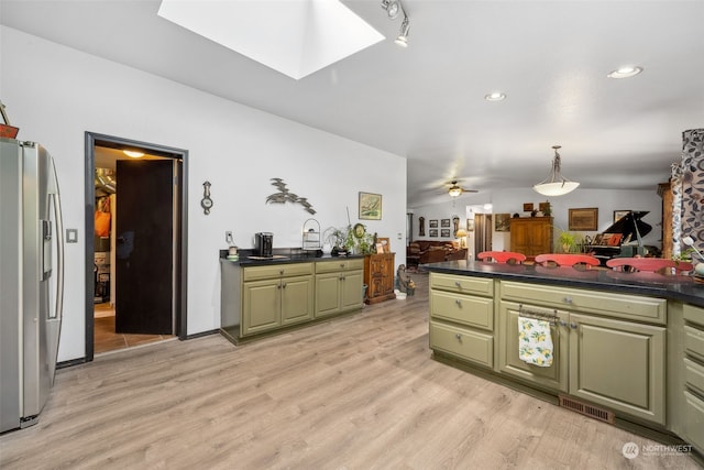 kitchen with a skylight, ceiling fan, light hardwood / wood-style flooring, green cabinets, and stainless steel refrigerator with ice dispenser