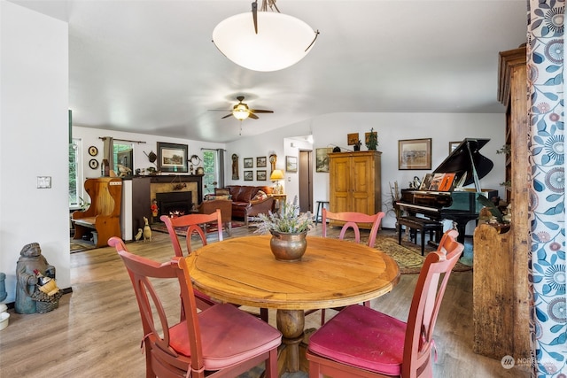 dining room with light wood-type flooring, ceiling fan, and vaulted ceiling