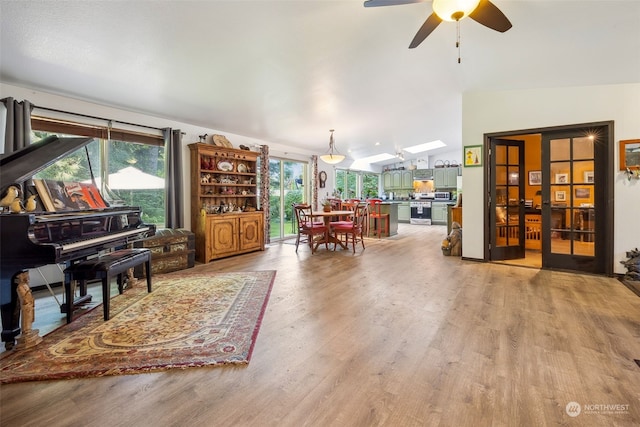 sitting room with vaulted ceiling with skylight, hardwood / wood-style flooring, and ceiling fan