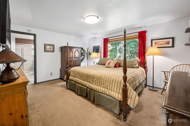 bedroom featuring light colored carpet, ensuite bath, and a textured ceiling