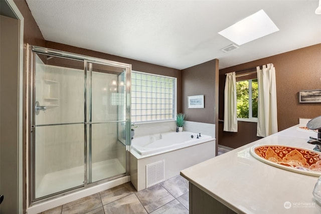 bathroom with a skylight, a textured ceiling, vanity, and shower with separate bathtub