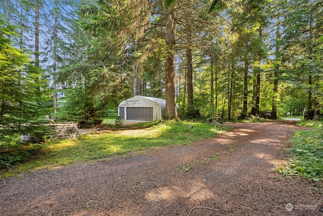 54611 278th Ave E, Ashford, WA 98304 - view of yard featuring a garage, a forest view, an outdoor structure, and dirt driveway