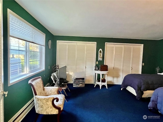 bedroom with baseboard heating, carpet floors, and two closets