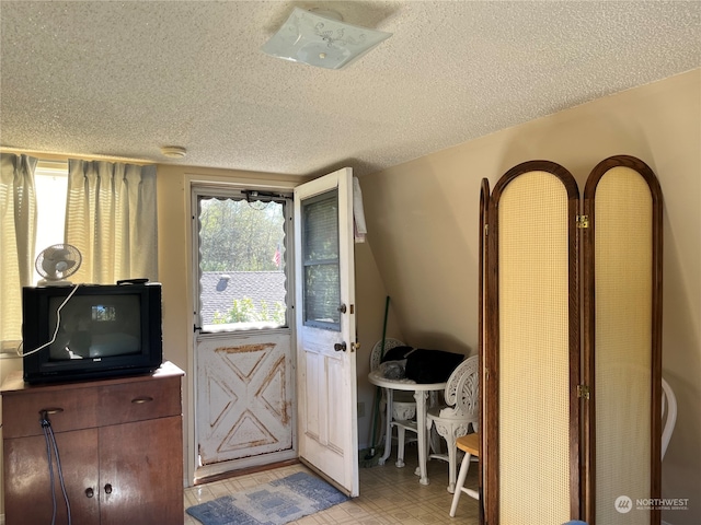 doorway to outside with a textured ceiling