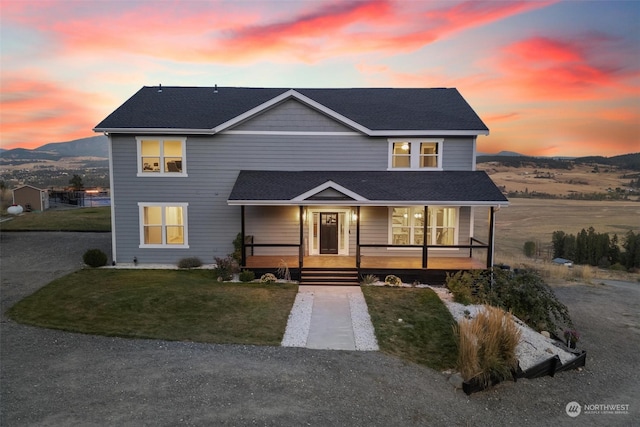 view of front property featuring covered porch, a mountain view, and a yard