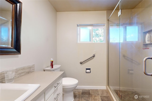 bathroom featuring vanity, a shower with shower door, and toilet