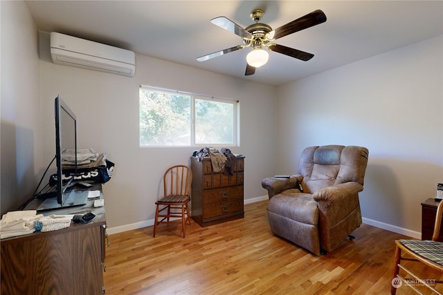 sitting room featuring ceiling fan, a wall mounted AC, and light hardwood / wood-style flooring