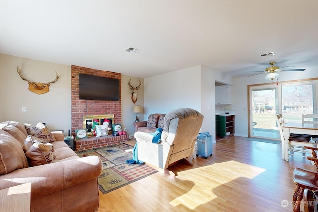 living room featuring hardwood / wood-style flooring, ceiling fan, and a fireplace