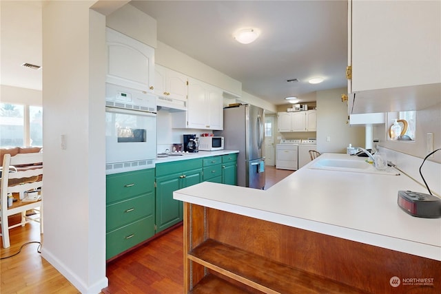 kitchen featuring sink, dark hardwood / wood-style flooring, white appliances, washing machine and dryer, and white cabinets