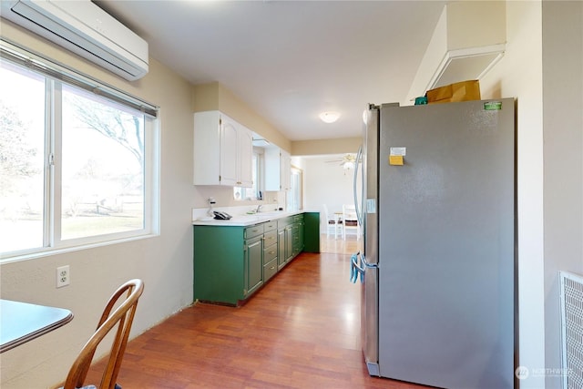 kitchen featuring sink, plenty of natural light, a wall unit AC, and stainless steel refrigerator