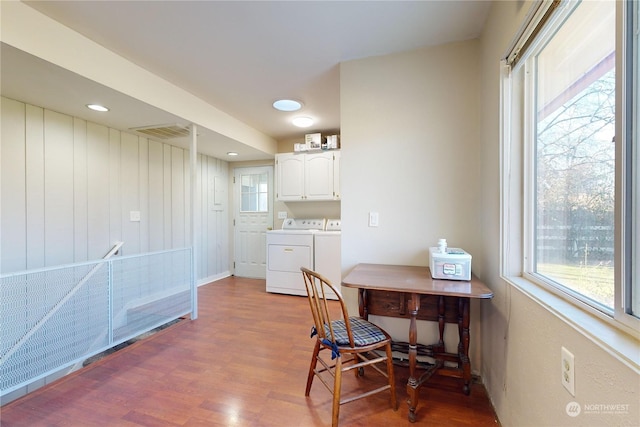 kitchen with hardwood / wood-style flooring, washer and dryer, and white cabinets