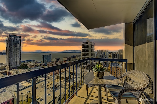 balcony at dusk featuring a water view