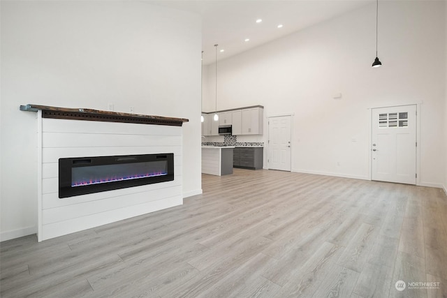 unfurnished living room featuring light hardwood / wood-style floors and a towering ceiling