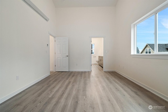 spare room featuring a towering ceiling and light hardwood / wood-style floors