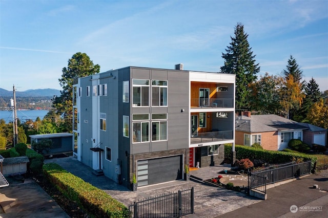 contemporary home featuring an attached garage, a mountain view, driveway, and fence