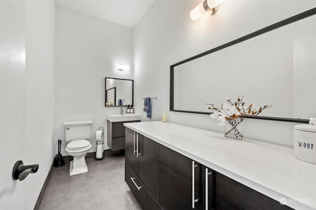 bathroom with tile patterned flooring, vanity, baseboards, and toilet