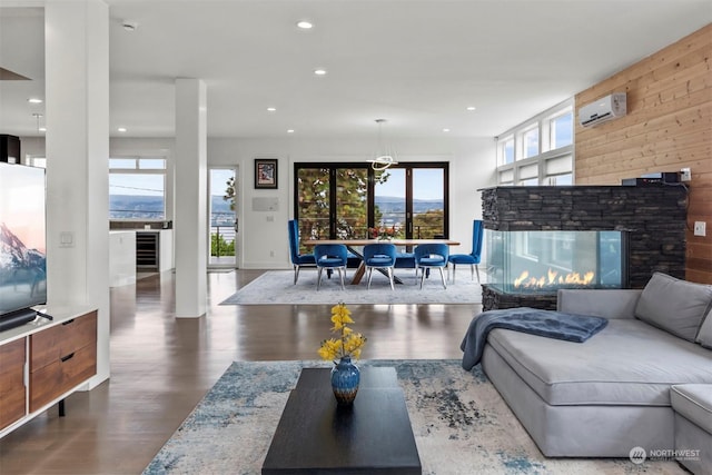 living room featuring baseboards, a stone fireplace, a wall mounted AC, recessed lighting, and wood finished floors