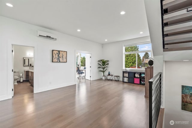 living area with recessed lighting, an AC wall unit, and wood finished floors