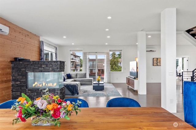 living room featuring recessed lighting, wooden walls, a stone fireplace, and wood finished floors