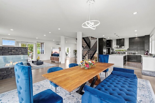 dining space featuring recessed lighting, stairway, light wood-style floors, and a stone fireplace