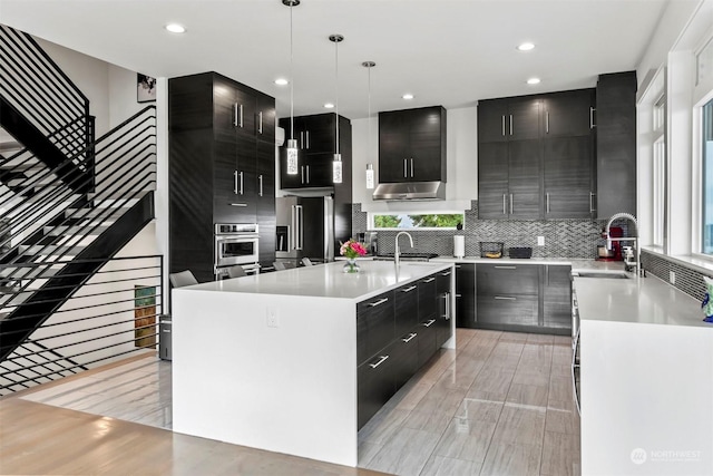 kitchen with dark cabinetry, a sink, modern cabinets, and stainless steel appliances