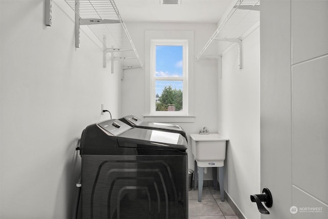 laundry area featuring laundry area, visible vents, a sink, baseboards, and washing machine and dryer