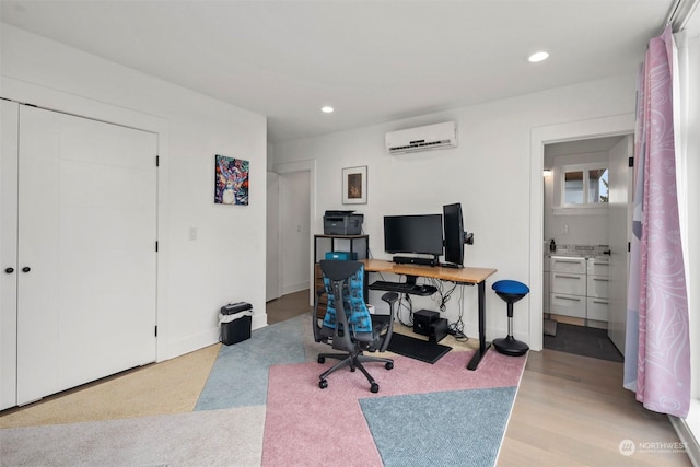 office space featuring recessed lighting, light wood finished floors, and an AC wall unit