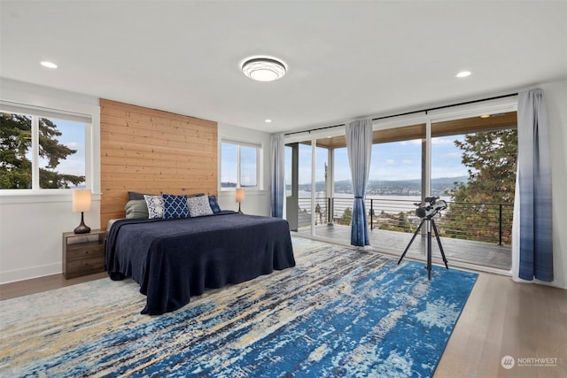 bedroom with access to outside, multiple windows, and wood finished floors