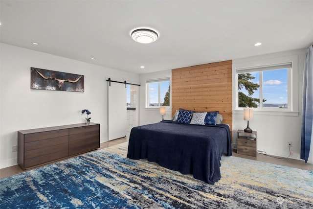bedroom featuring wood finished floors, recessed lighting, and a barn door