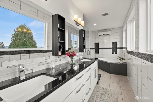 full bath with a sink, visible vents, a bath, and double vanity