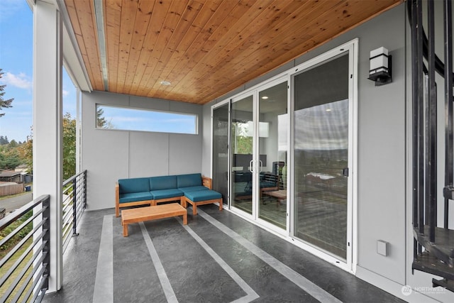 sunroom / solarium featuring finished concrete flooring, wooden ceiling, and an outdoor hangout area