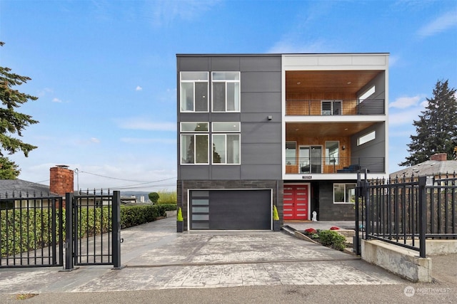 modern home featuring an attached garage, concrete driveway, fence, a balcony, and a gate