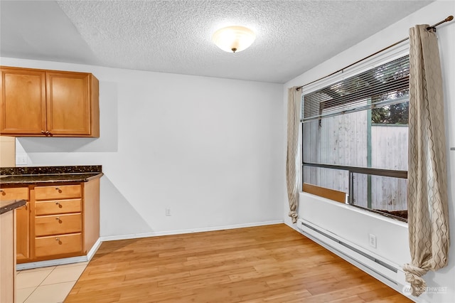 unfurnished dining area featuring a textured ceiling, light hardwood / wood-style flooring, and a baseboard heating unit