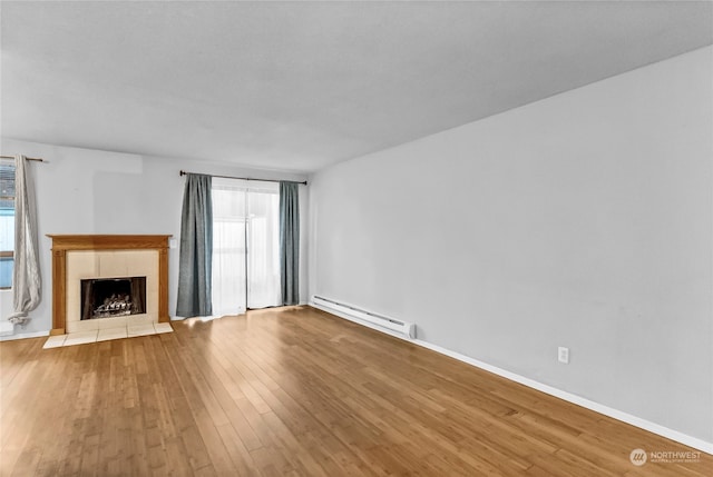 unfurnished living room featuring light hardwood / wood-style flooring, a baseboard heating unit, and a tile fireplace