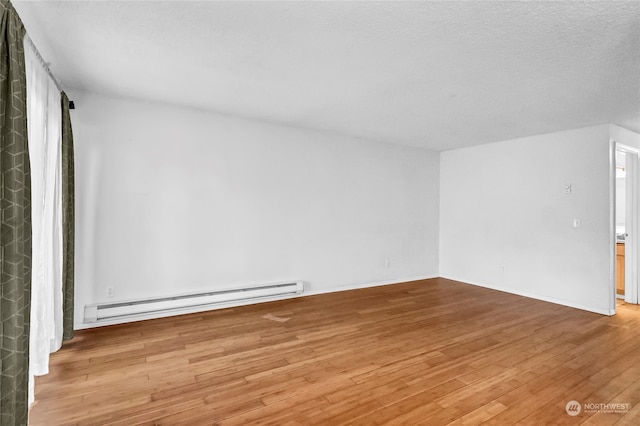 empty room featuring light wood-type flooring, a baseboard radiator, and a textured ceiling