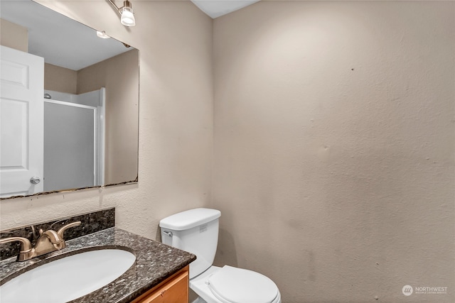 bathroom featuring a shower with shower door, vanity, and toilet