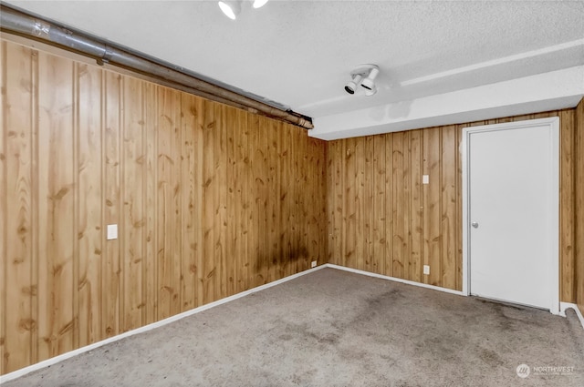 carpeted spare room with a textured ceiling and wooden walls