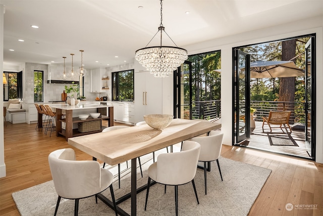 dining space with a healthy amount of sunlight, light hardwood / wood-style flooring, and a notable chandelier