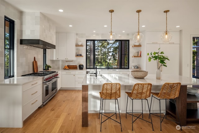 kitchen with tasteful backsplash, white cabinetry, light wood-type flooring, pendant lighting, and double oven range