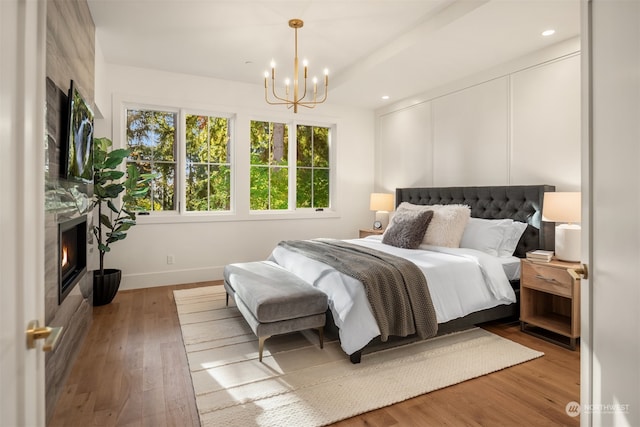 bedroom featuring hardwood / wood-style flooring, a high end fireplace, and an inviting chandelier