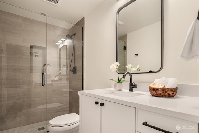 bathroom featuring an enclosed shower, vanity, and toilet