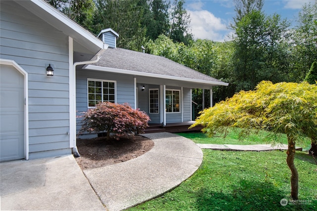 view of exterior entry featuring a garage and a lawn