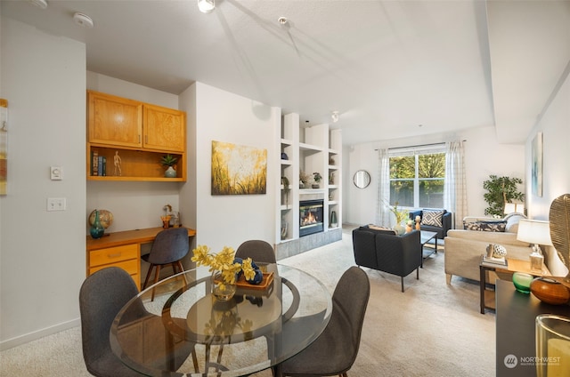 carpeted dining area with built in desk and a fireplace