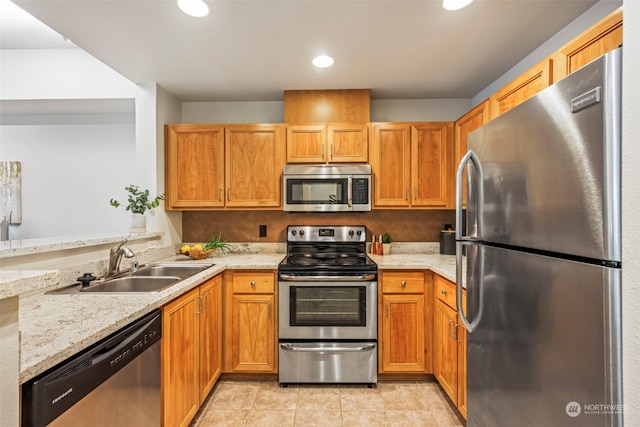 kitchen with kitchen peninsula, sink, light tile patterned flooring, appliances with stainless steel finishes, and light stone counters