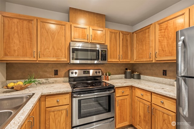 kitchen featuring light stone countertops, sink, and appliances with stainless steel finishes